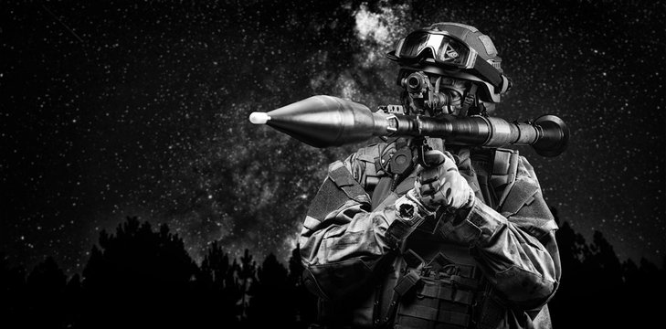 American soldier aims at the sight of an RPG against the background of a night forest. The concept of military special operations.