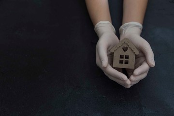 stay at home . girl holding a wooden house on the black background