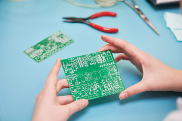 Microcontroller circuit board manufacture. Technician's hand with pcb