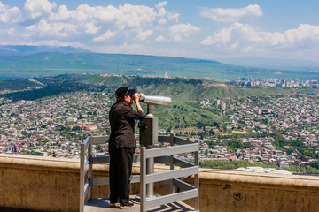 Fototapeta na wymiar Tourist looking from binocular from Mt Mtatsminda above old Tbilisi. Georgia