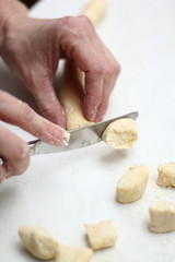 Fototapeta na wymiar Gnocchi being prepared. Cutting dough. Dough dumplings with cheese.
