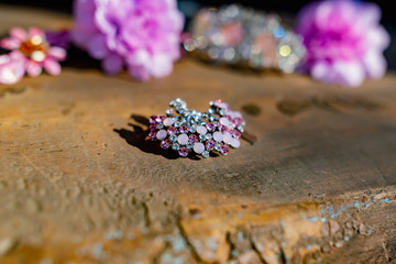 A composition of women's jewelry and accessories in pink on an old wooden surface. Brooch with colored stones, hairpins and flowers in delicate shades