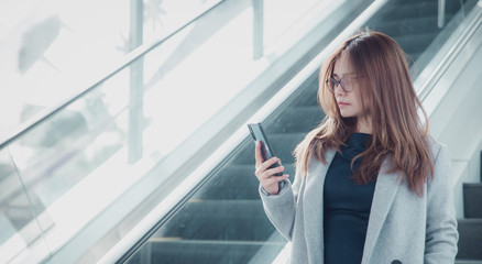 Beautiful confident businesswoman talking something on smart phone and walking inside in airport.