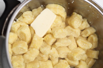 Gnocchi being prepared. Adding butter into cooked dumplings. Dough dumplings with cheese.