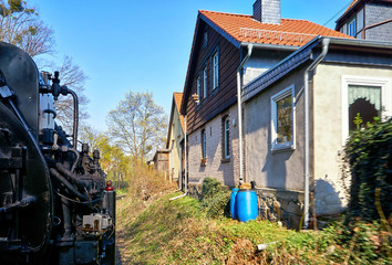 Steam locomotive drives past the houses. Dynamic through motion blur.