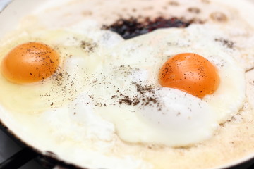 Sprinkle with pepper. Making sunny side up eggs with black pepper and salt.