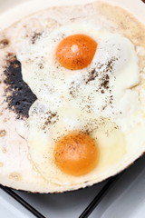 Making sunny side up eggs with black pepper and salt.