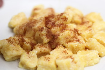 Adding cinnamon in Gnocchi. Small soft dough dumplings with cottage cheese on plate.