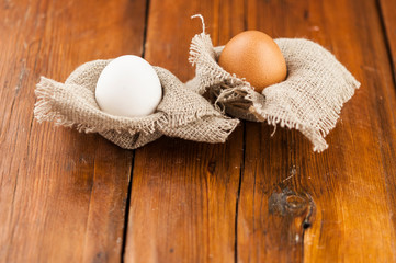 Fototapeta na wymiar Eggs stand on a burlap that stands on a brown wooden table. Top views with clear space