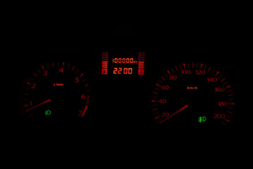 Black automobile dashboard with orange lights of odometer and green headlights symbols  Selective...