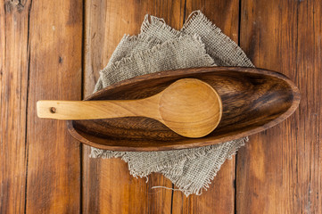 Fototapeta na wymiar rustic style. Empty wooden bowl, and wooden spoon on wood table with burlap tablecloth
