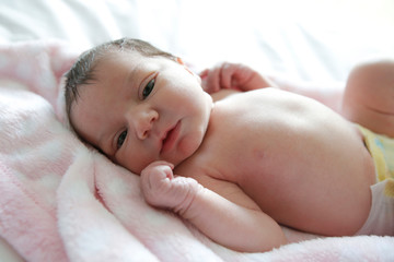 A newborn baby lays on a white bed