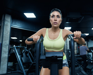Fototapeta na wymiar Fit woman using exercise bike in gym.