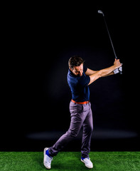 Close-up of a golf player intent on perfecting the swing isolated on dark background, full length