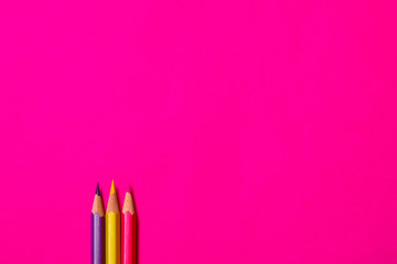 Multi colored crayons at magenta background with copy space