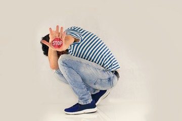 Man ME TOO. The man covers his head, curls up and has his hand outstretched, with a stop sign on his palm.Man in defensive position, showing gesture stop. Curled person on white background.