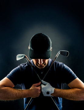 Close-up of a golf player with golf irons crossed on his chest, isolated on black background, vertical image
