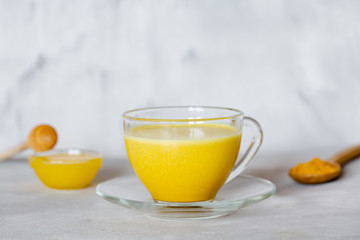 Golden milk in a glass mug on a gray background. Healthy drink from india.