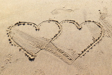 two hearts drawn on the sea sand