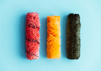 Paint rollers side by side in a row isolated on a blue background