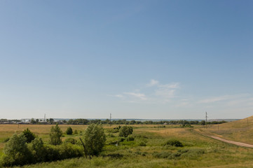 Suburb and villages. Big mountains and green forests. Trees and their shadows on the grass. Summer day with dark blue and grey sky and  clouds. Fields. Fresh air.