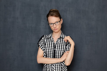 Portrait of serious focused woman with glasses, holding arms folded