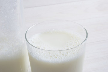 Vaso de leche y botella con tapón en la mesa blanca