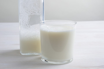 Vaso de leche y botella con tapón en la mesa blanca