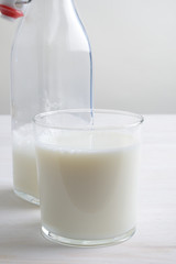 Vaso de leche y botella con tapón en la mesa blanca