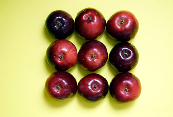 Nine fresh red apples on a yellow background.