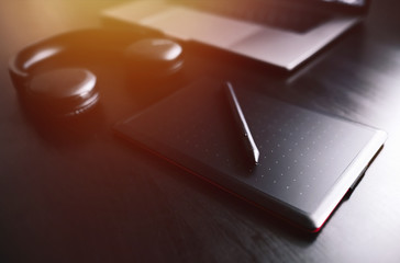 Dark modern workplace with a graphic tablet, laptop, wireless headphones 