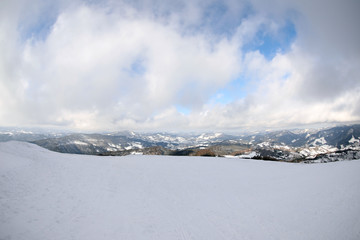 Picturesque mountain landscape with snowy hills under cloudy sky