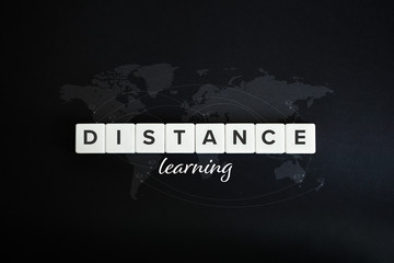 Distance, online learning and e-learning concept. Block letters, cursive type and world map on black background.
