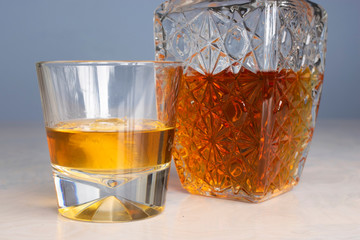 Whisky glass decanter hall-full with whisky liquor and an empty glass of whiskey on table front view