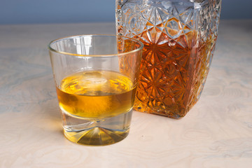 Whisky glass decanter hall-full with whisky liquor and an empty glass of whiskey on table front view