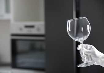 Person in white glove checking cleanliness of glass indoors, closeup. Space for text