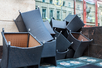 Pile of waste unnecessary wicker armchair closed outdoor sidewalk cofe. Small business end problem...