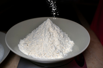 Pouring flour into a deep plate. High angle.