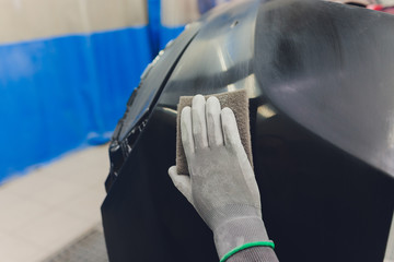 Auto mechanic preparing the car for paint job by applying polish with the power buffer machine