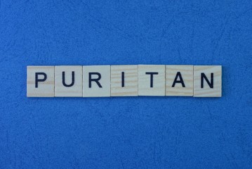Text from a short word puritan from gray small wooden letters on a blue table