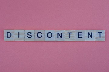 long gray word discontent made of small wooden letters with black font on an orange background