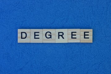 inscription from a short word degree from gray square wooden letters on a dark blue table