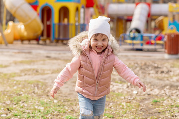 Little girl walks on the playground in the street
