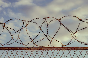 Barbed wire against the sky with clouds. The prohibition of air travel.
