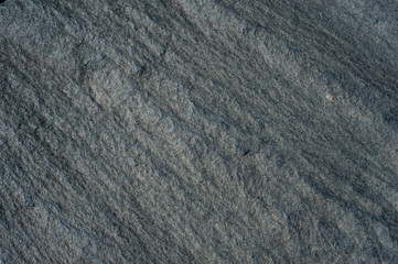 Natural stone of grey color with a chipped uneven texture background