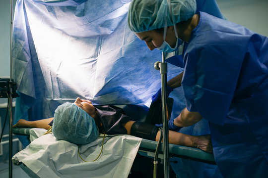 Anesthetist applying blood pressure cuff to patient in operating room