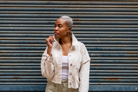 Woman standing at a roller shutter looking sideways