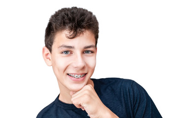 A teenage boy is genuinely smiling and showing off his healthy white teeth with braces for...