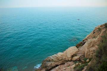 The prominent horizon of the Mediterranean Sea with a rocky shore. On the rock there are steps going down to the water itself.