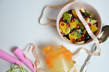 Fitness, healthy fruits, Fresh healthy salad, diet and active lifestyles Concept, dumbbells, fresh fruits, bottle for water, measure centimeter, jump rope on a white background . copy space for text.